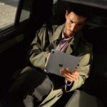 A passenger in the back of a car looks at the new iPad Pro with M5 on the go.